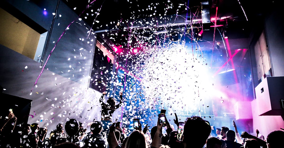 Energetic nightclub scene with crowd dancing under confetti and colorful lights.